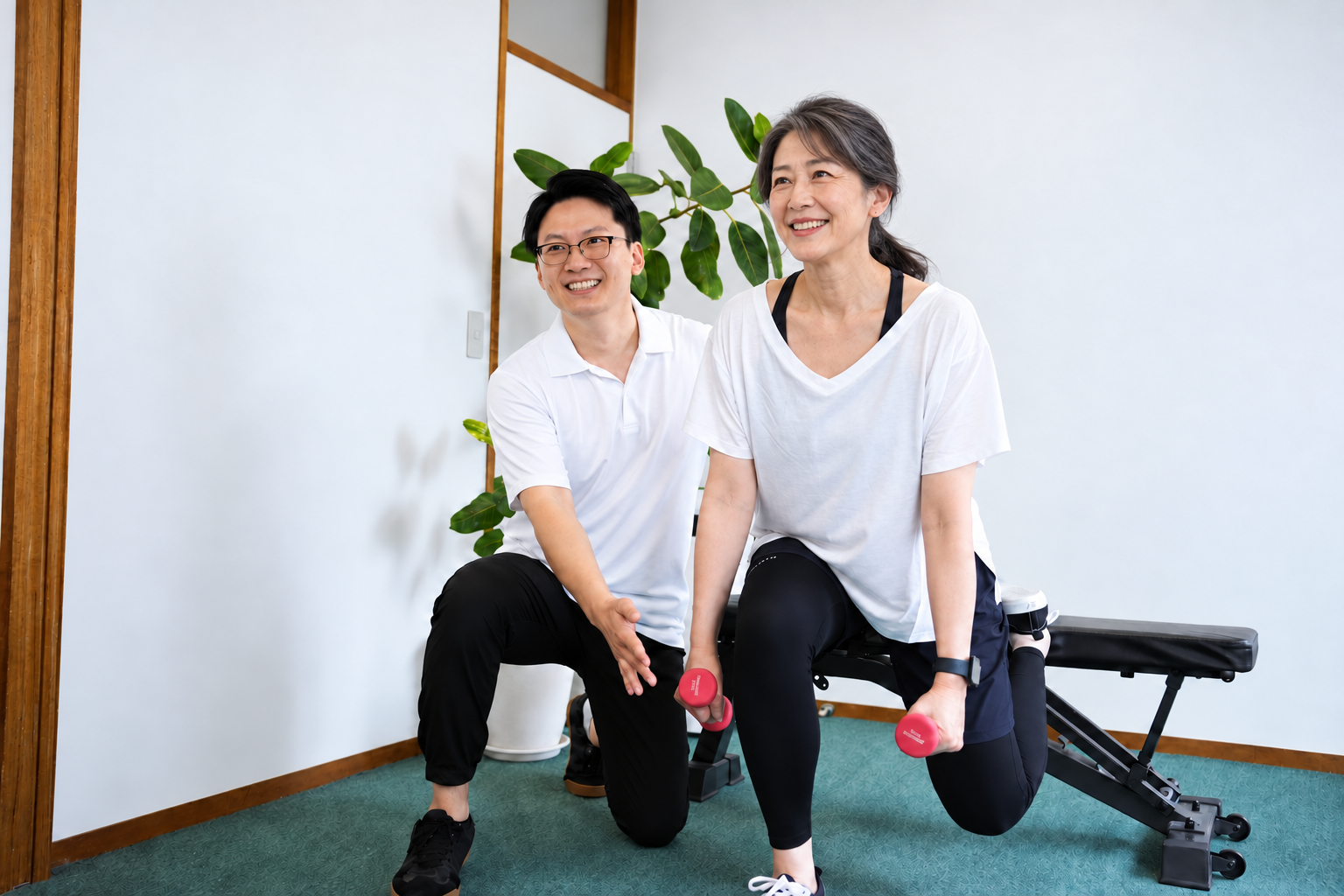 白いウェアの女性が、トレーナーのサポートを受けながらダンベルを持って片脚のトレーニングをしているイメージ写真